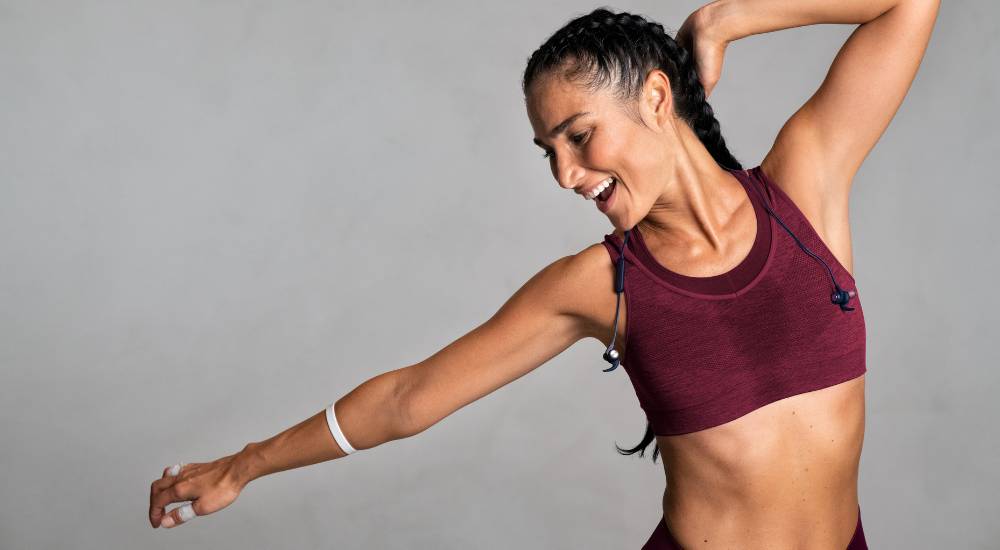 Young athletic woman smiling while stretching before workout