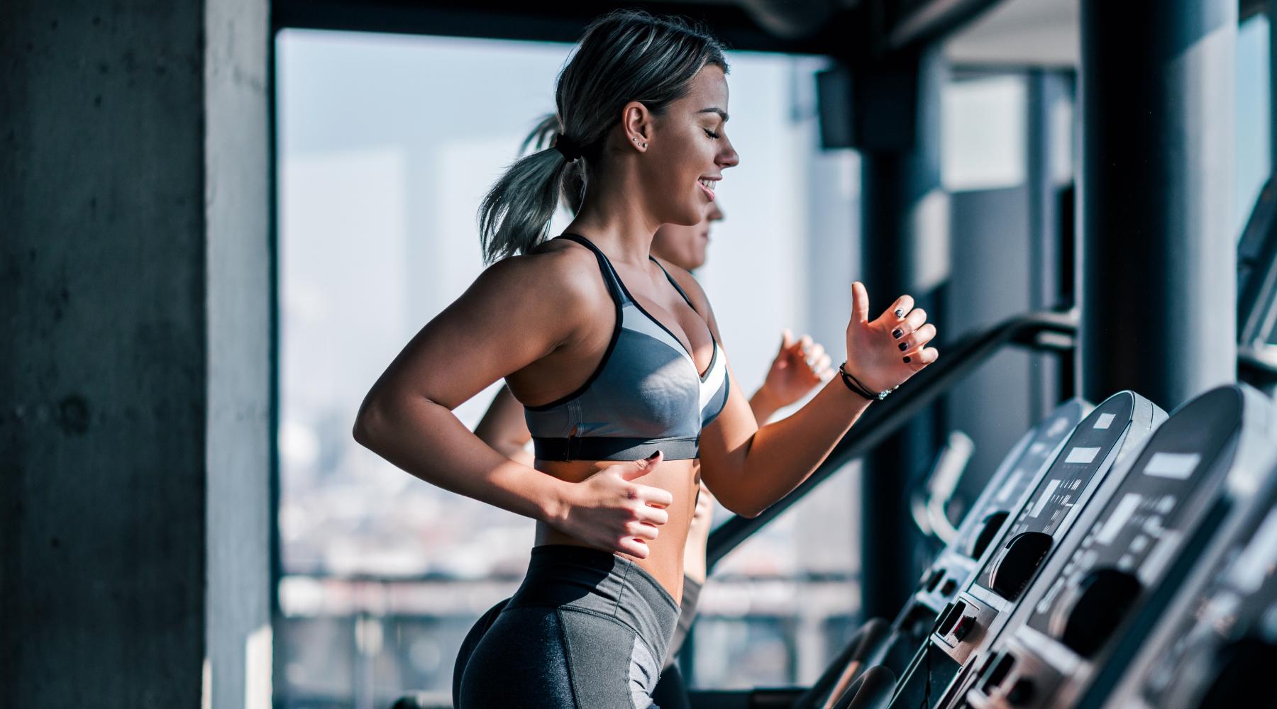 Attractive young woman burning calories cardio workout treadmill gym