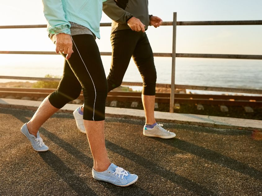 Older couple in athletic wear brisk walking outdoors