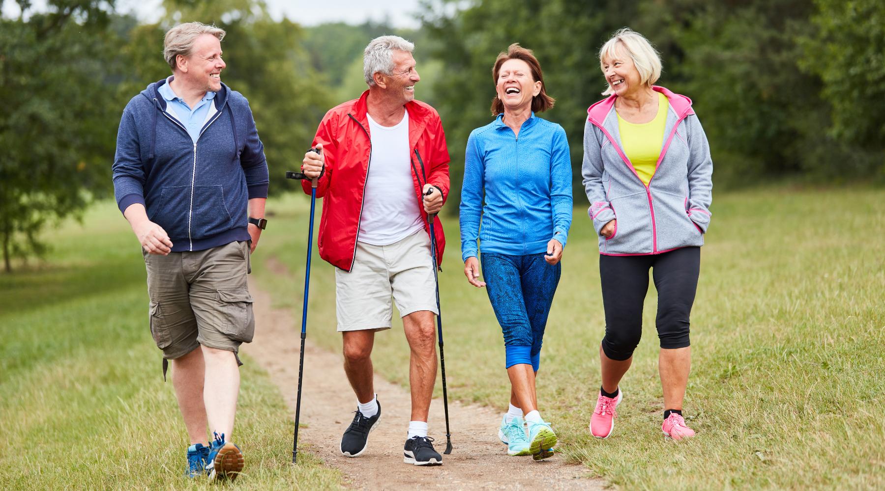 Two senior couples walking outdoors on nature trail