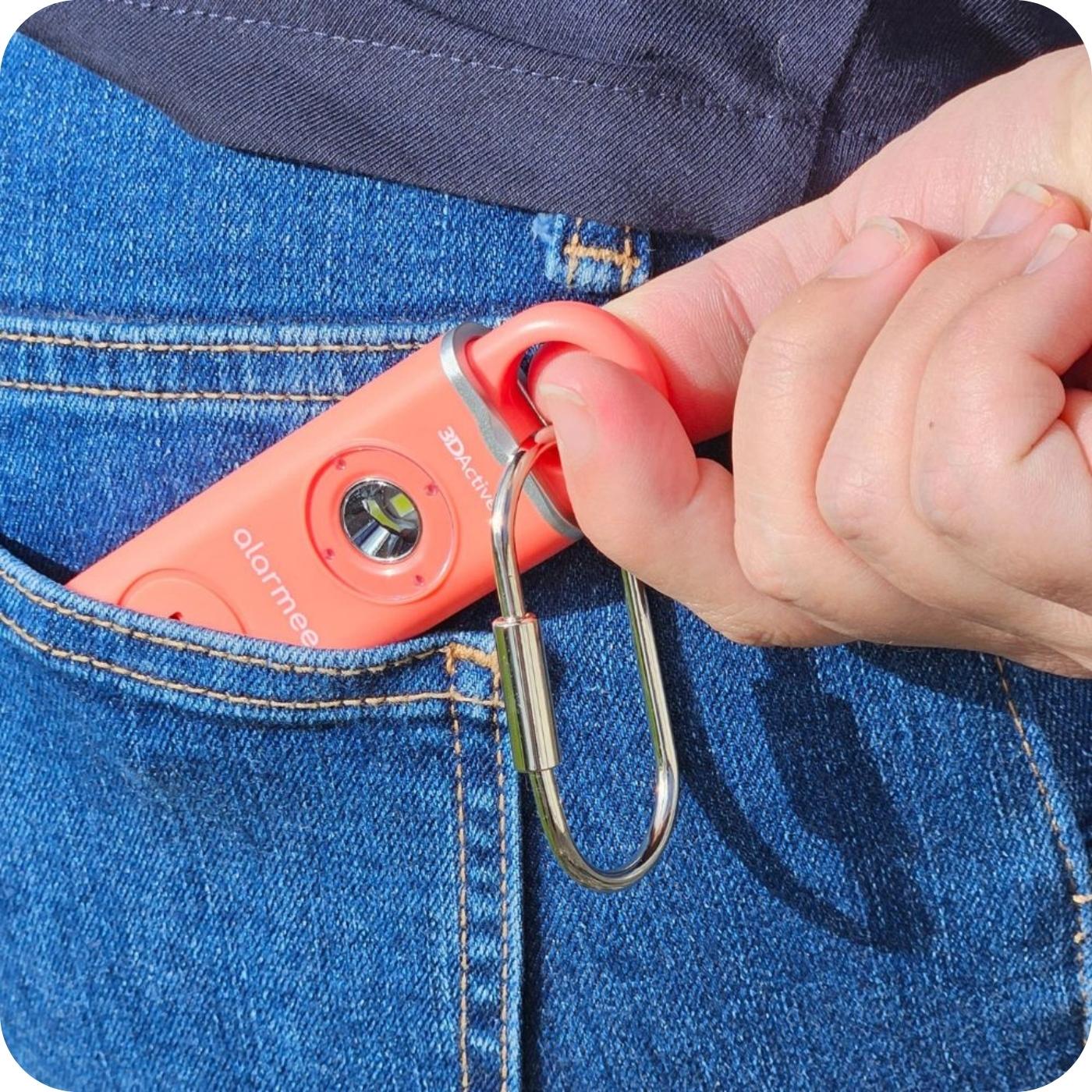 Hand placing self defense keychain (Alarmee) in back pocket