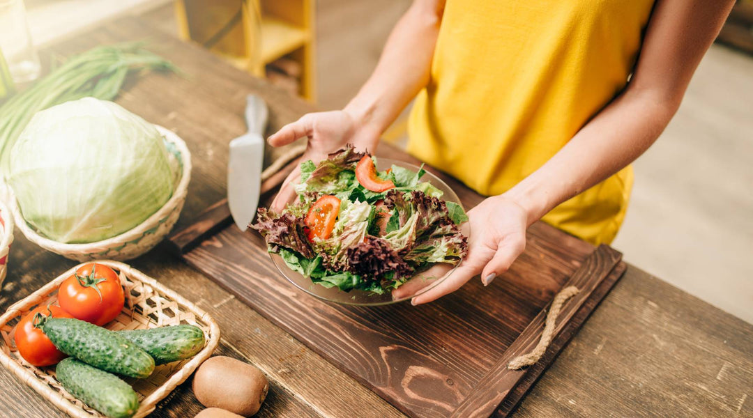 Female person cooking salad on the kitchen, healthy organic food preparing. Vegetarian diet, fresh vegetables and fruits on wooden table