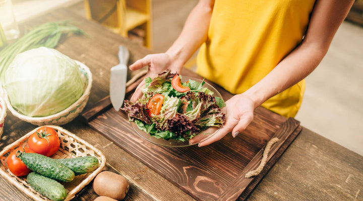 Female person cooking salad on the kitchen, healthy organic food preparing. Vegetarian diet, fresh vegetables and fruits on wooden table