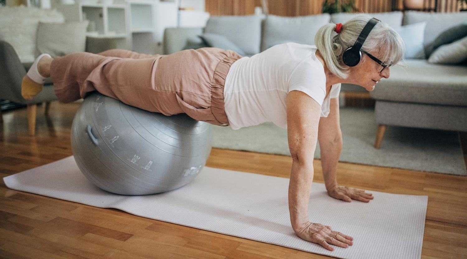 Senior woman doing balance exercise with yoga ball at home