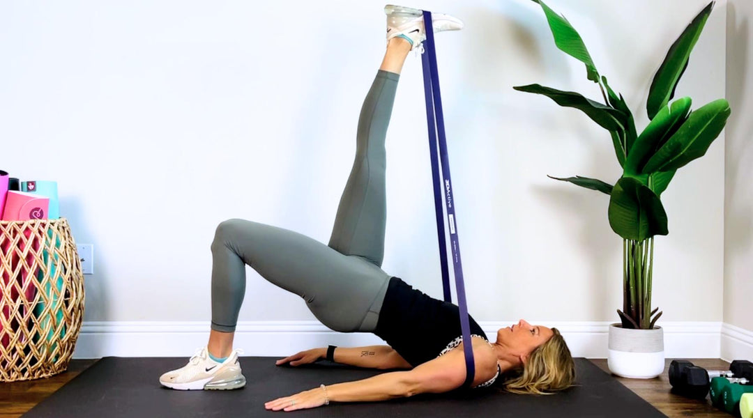Young fit woman doing exercise with resistance band at home