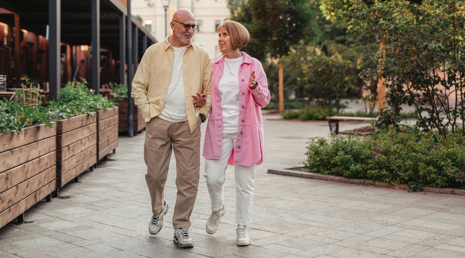 Happy and healthy elderly couple holding arms while walking outdoors