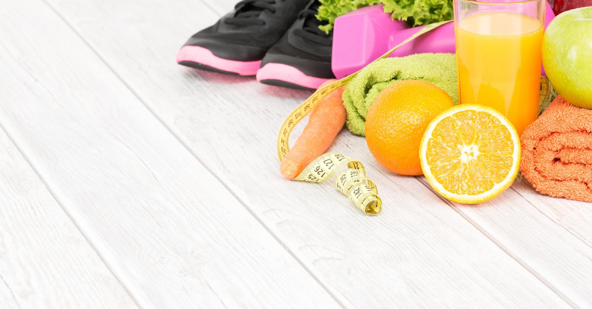 Running shoes, sports towels, oranges, orange juice, and measuring tape on top of a wooden floor.