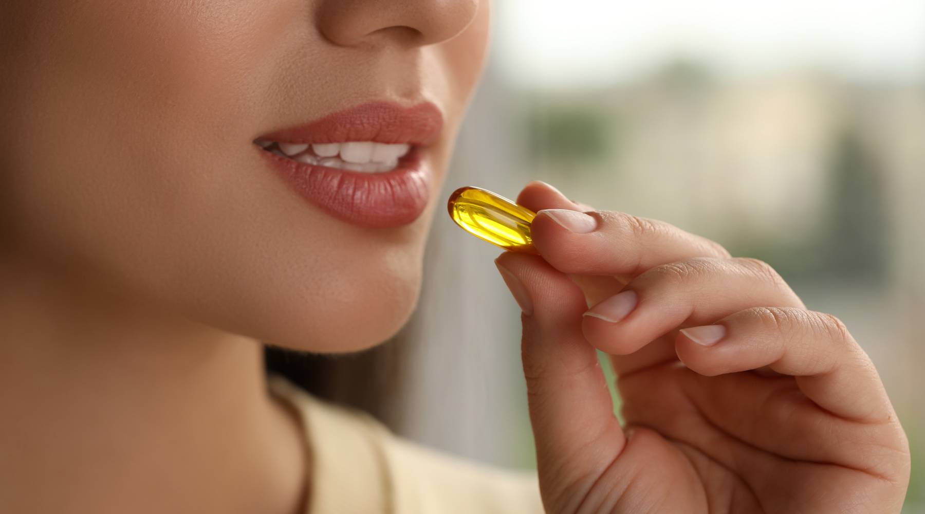 Young woman preparing to take dietary supplement capsule