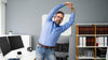 Office worker stretching arms at his desk