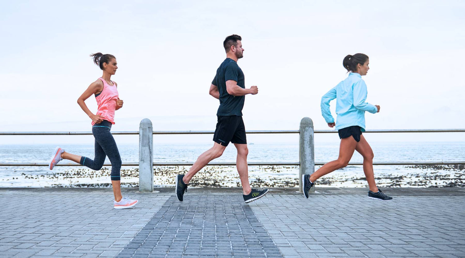 Shot of a group of young people running on a promenade