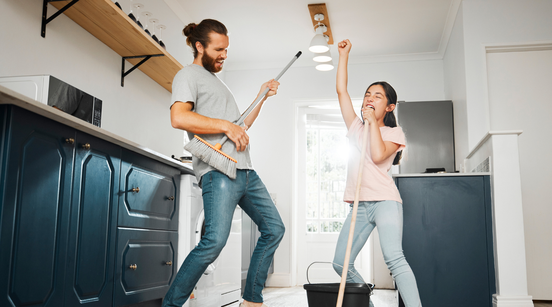 Young couple having fun dancing while cleaning their house