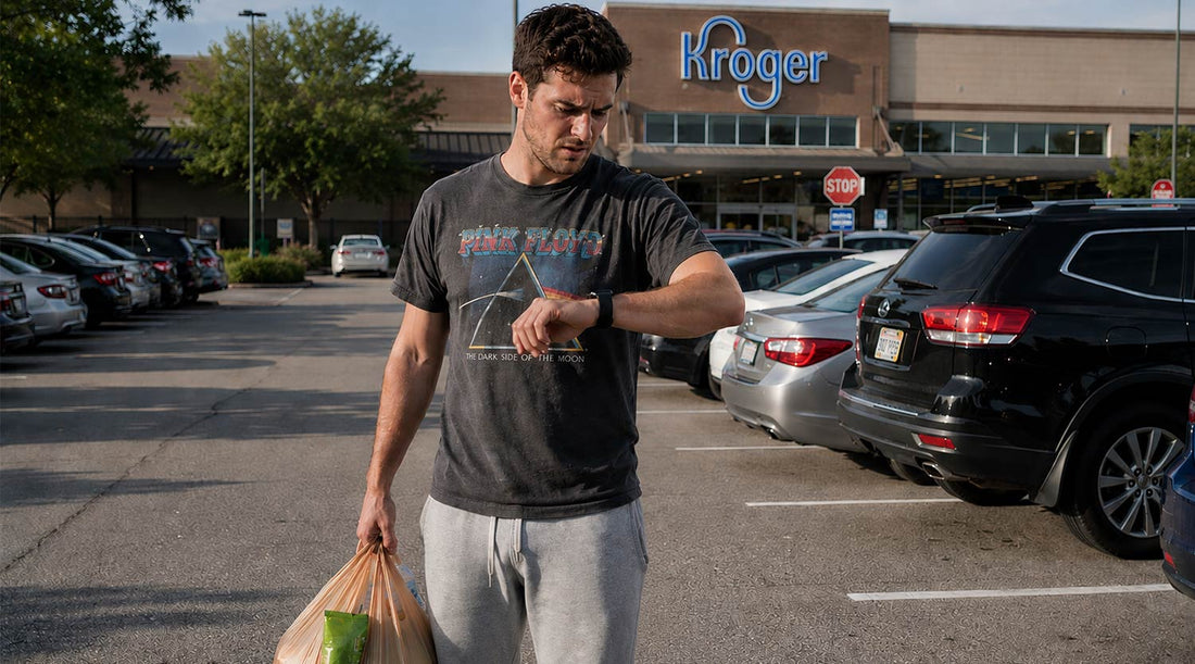 Young man holding grocery bags checking low step count on Apple Watch in car park