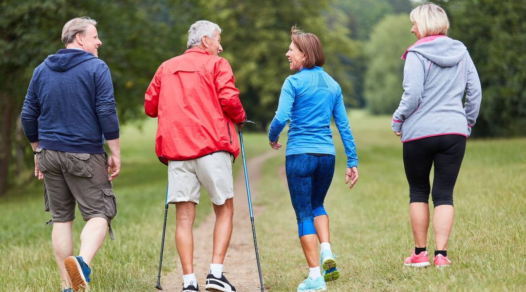 Two senior couples in hiking clothes walking outdoors for their health