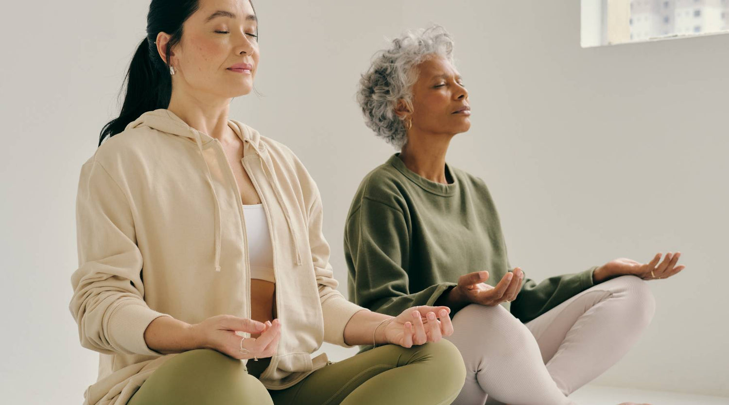 Young Asian woman and older African-American woman meditating indoors
