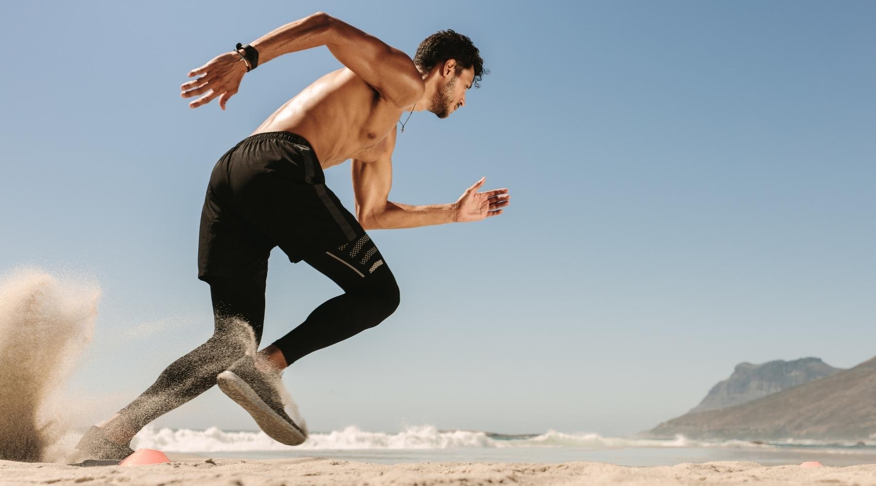 Shirtless muscular man running at the beach