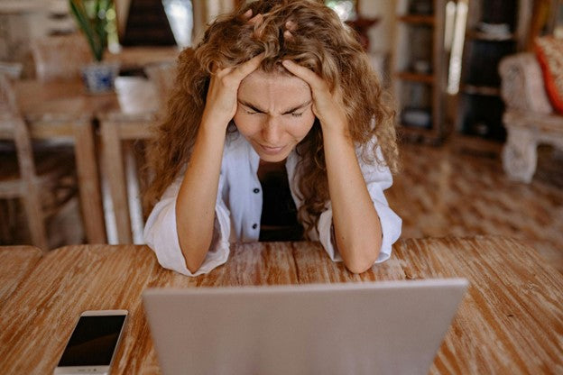 Stressed woman rubbing her forehead in front of laptop