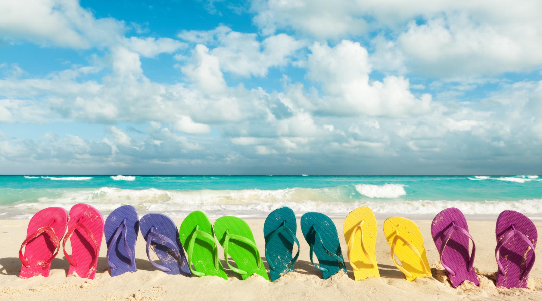 Stay Safe during Spring break - a row of flip flops on a sandy beach. 