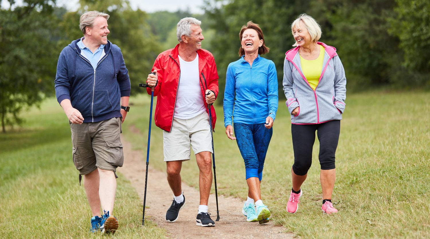 Two senior couples walking outdoors on nature trail