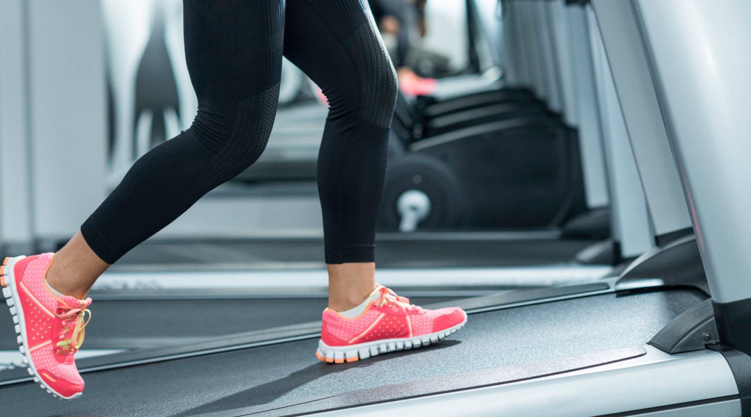 Woman with pink walking shoes stepping on treadmill for walking workout