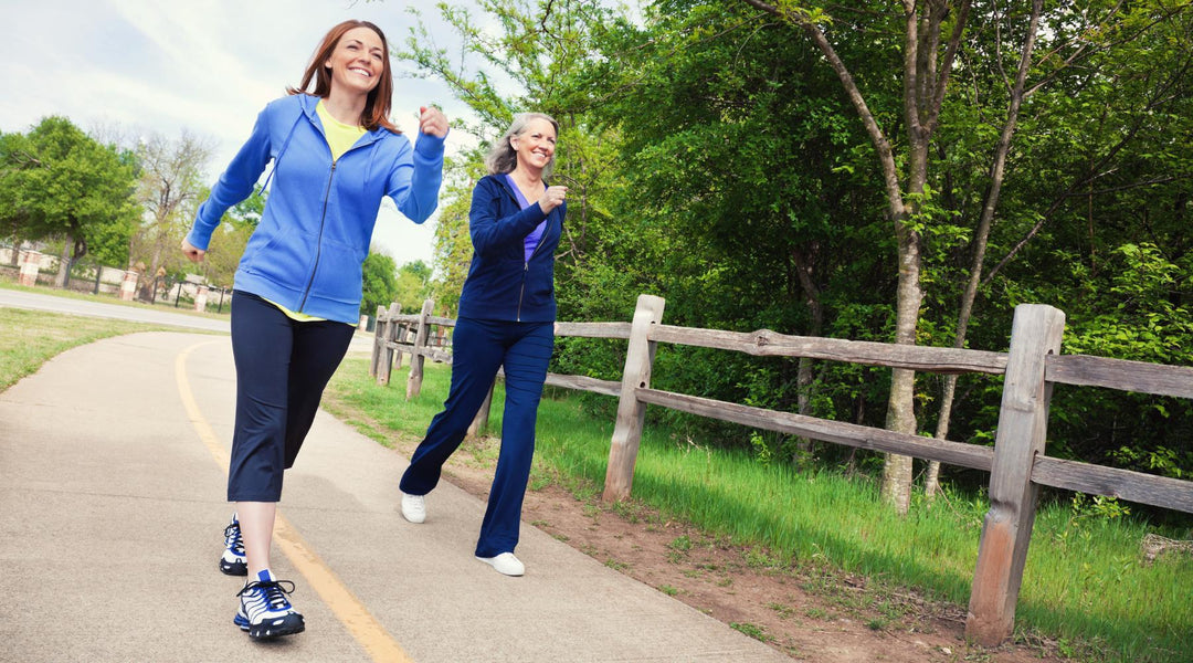 Two women power walking outdoors in a rural area