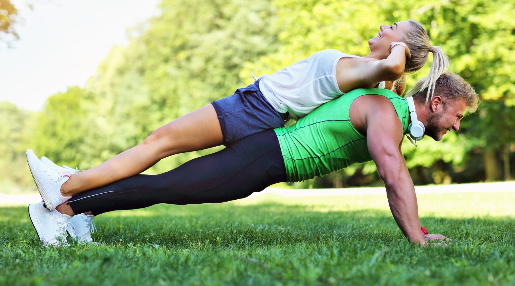 Man doing a push-up with a woman lying on his back