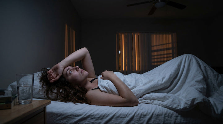 Young woman lying awake in dark apartment bedroom unable to sleep