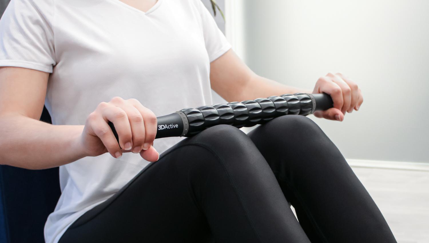 Woman using muscle roller stick on her thighs